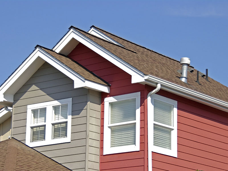 Red house featuring a newly installed gutter system by MJC Contracting